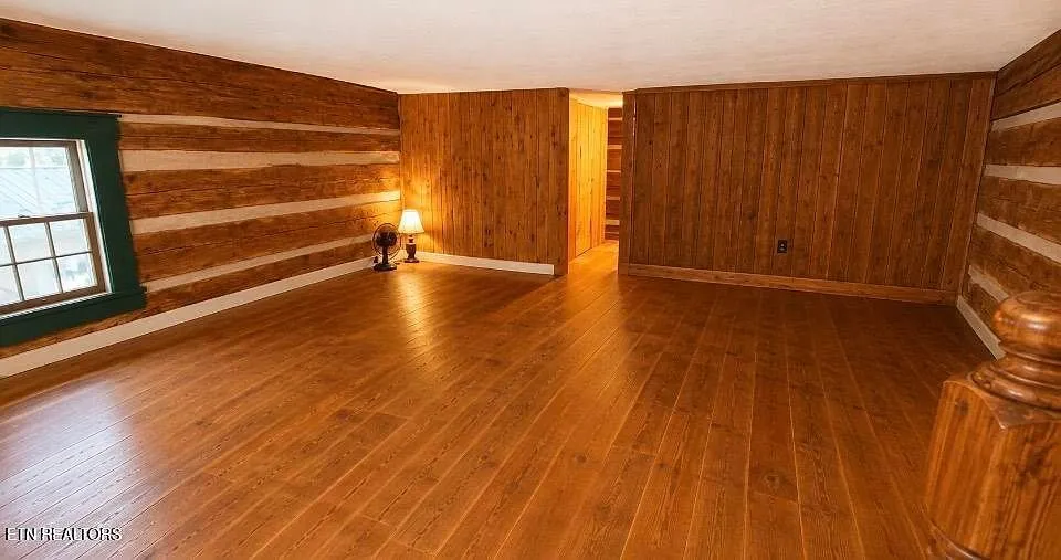 A log-walled room with a wall lamp and wood floor