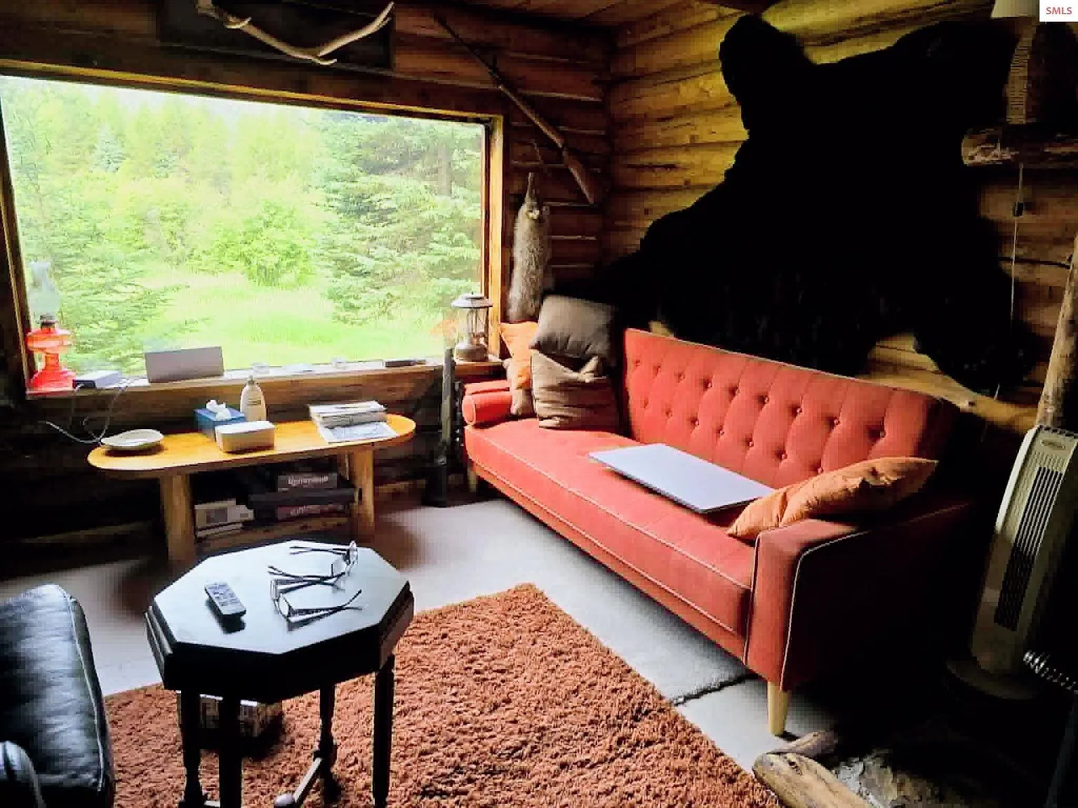A leather recliner and wood stove flue rising through the open loft above