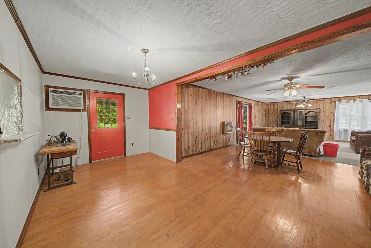 The dining area with a red door and a table under a light fixture