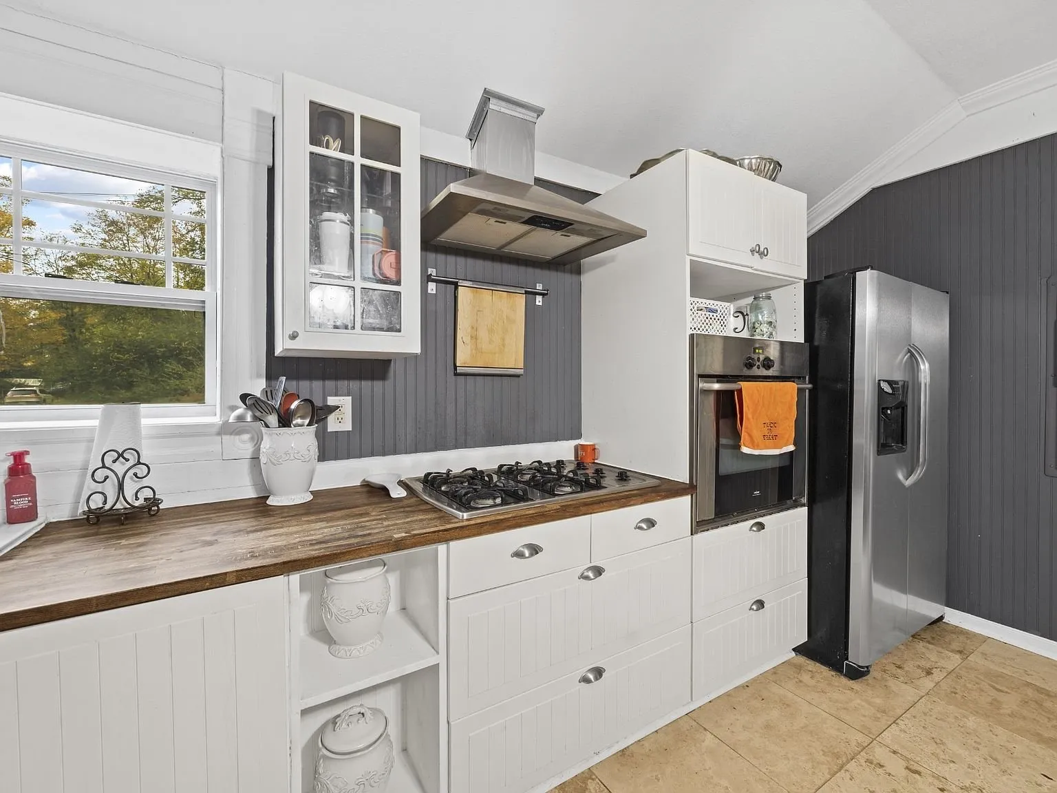 Kitchen work wall with the gas cooktop, wall oven, and stainless refrigerator