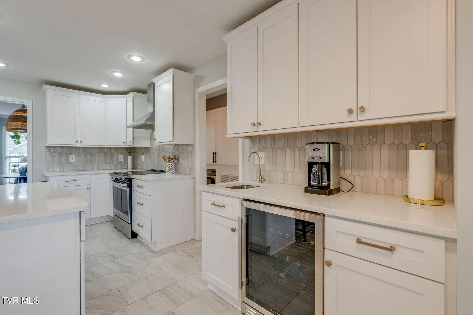 The kitchen cabinetry and range wall with the tile backsplash
