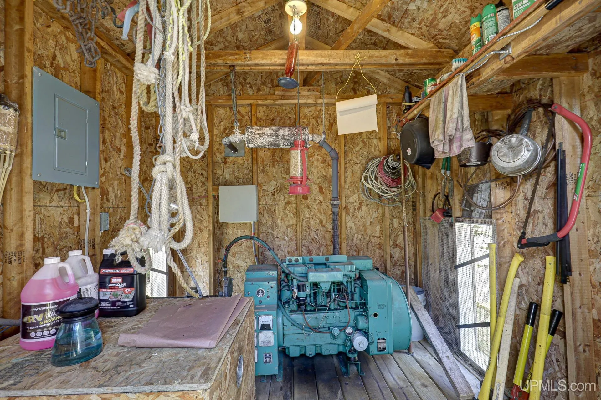 The generator inside its building, cables and tools on the wall