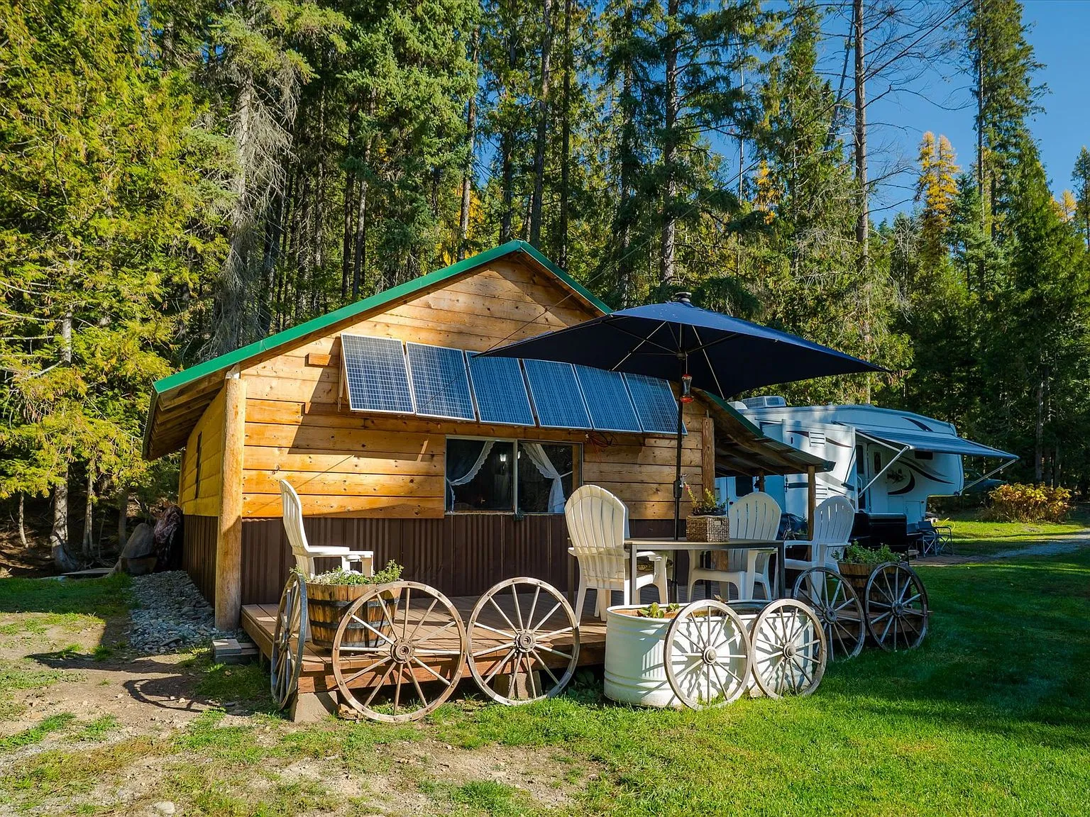 The log storage building with a green metal roof and open lean-to bay