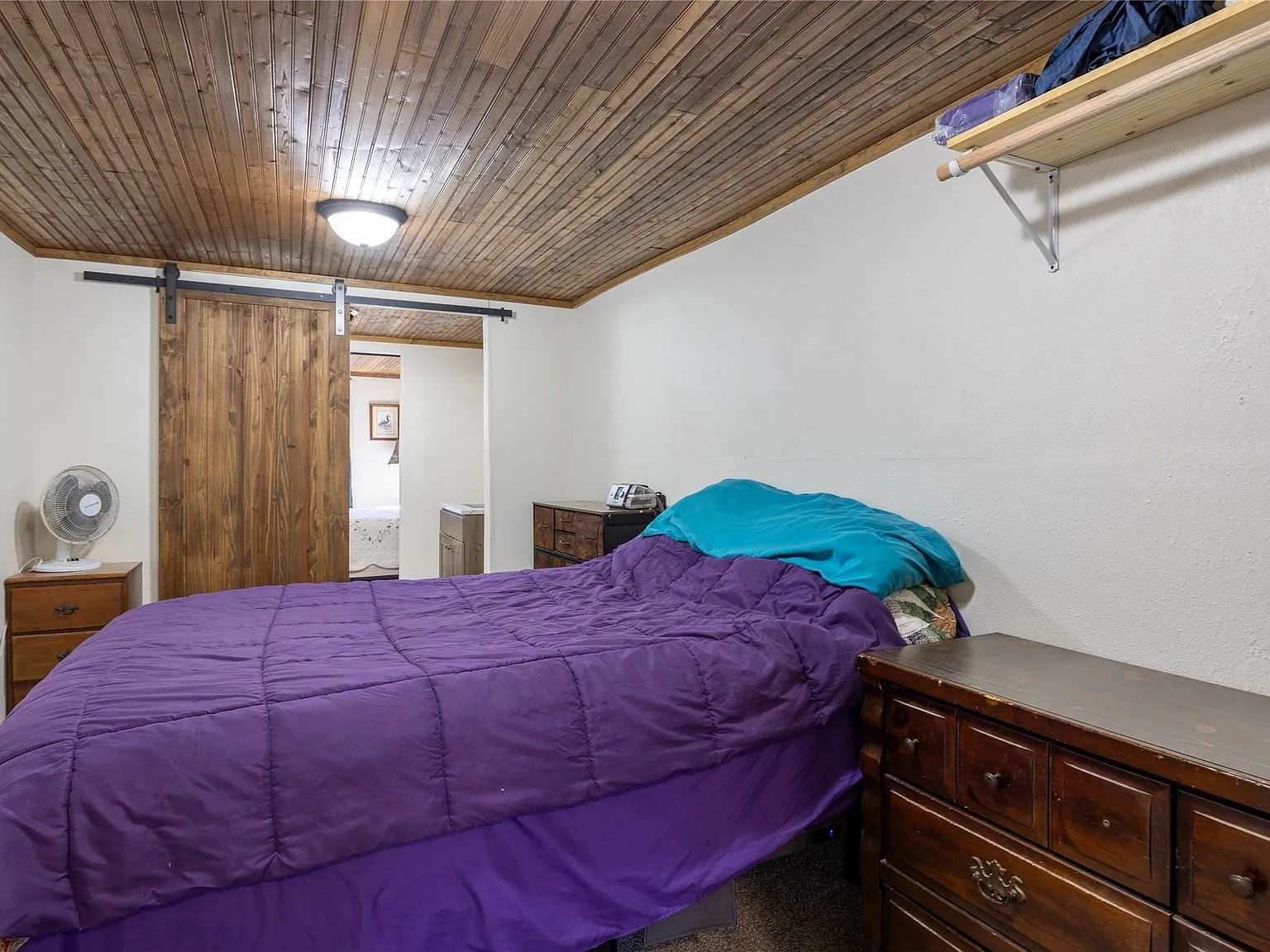 A bedroom with a dresser and closet space