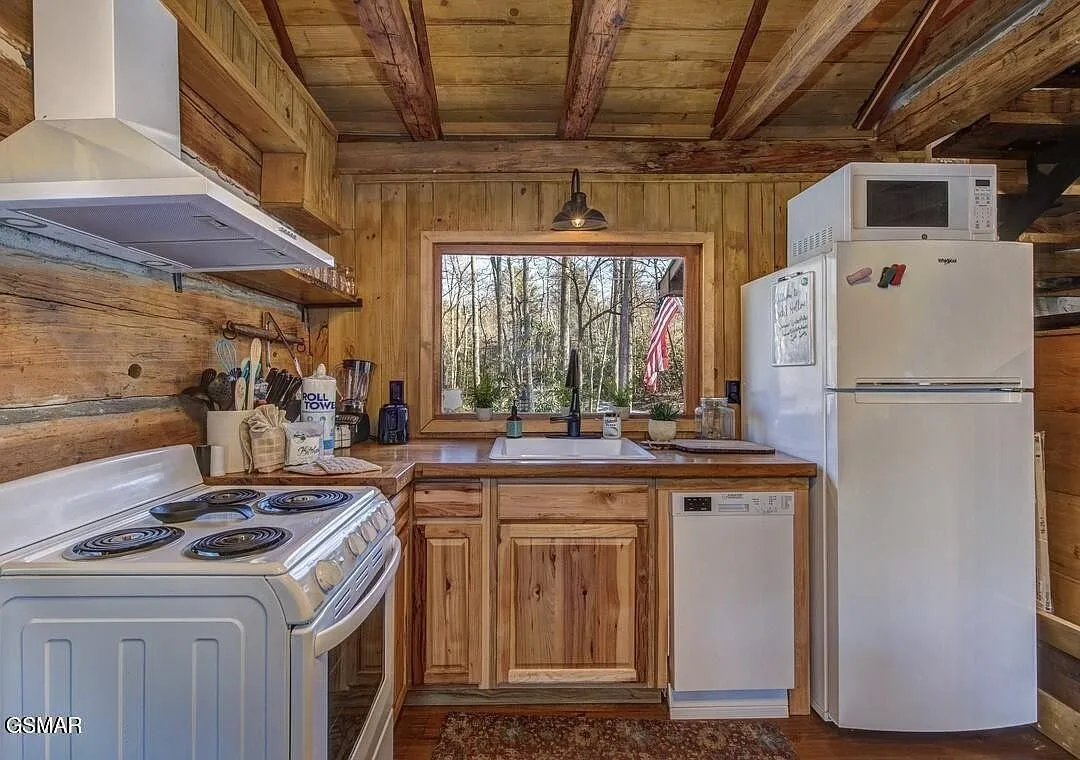 The kitchen with a range, vent hood, dishwasher and refrigerator
