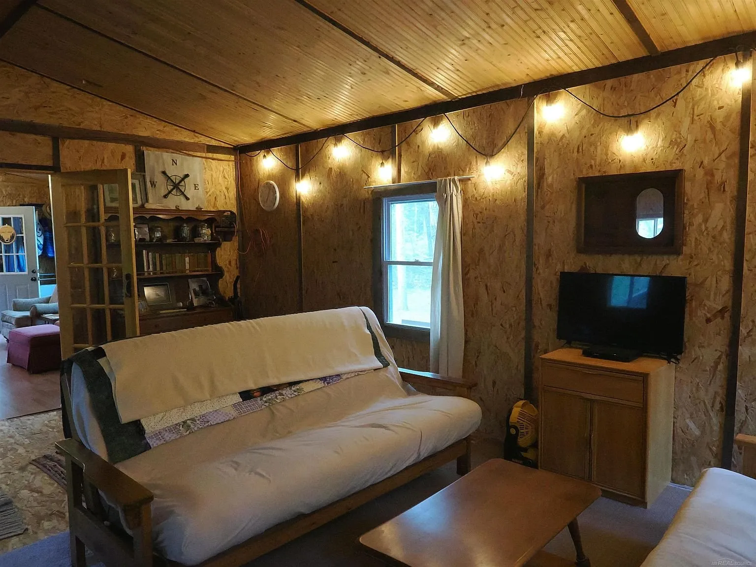 The futon in the bunk room with the television on the cabinet