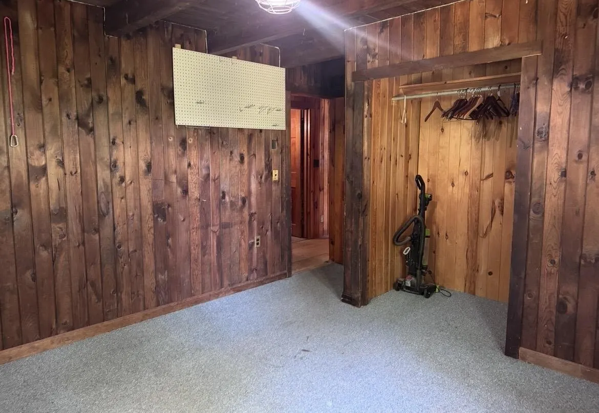 A bedroom with the open closet, the pegboard and the vacuum