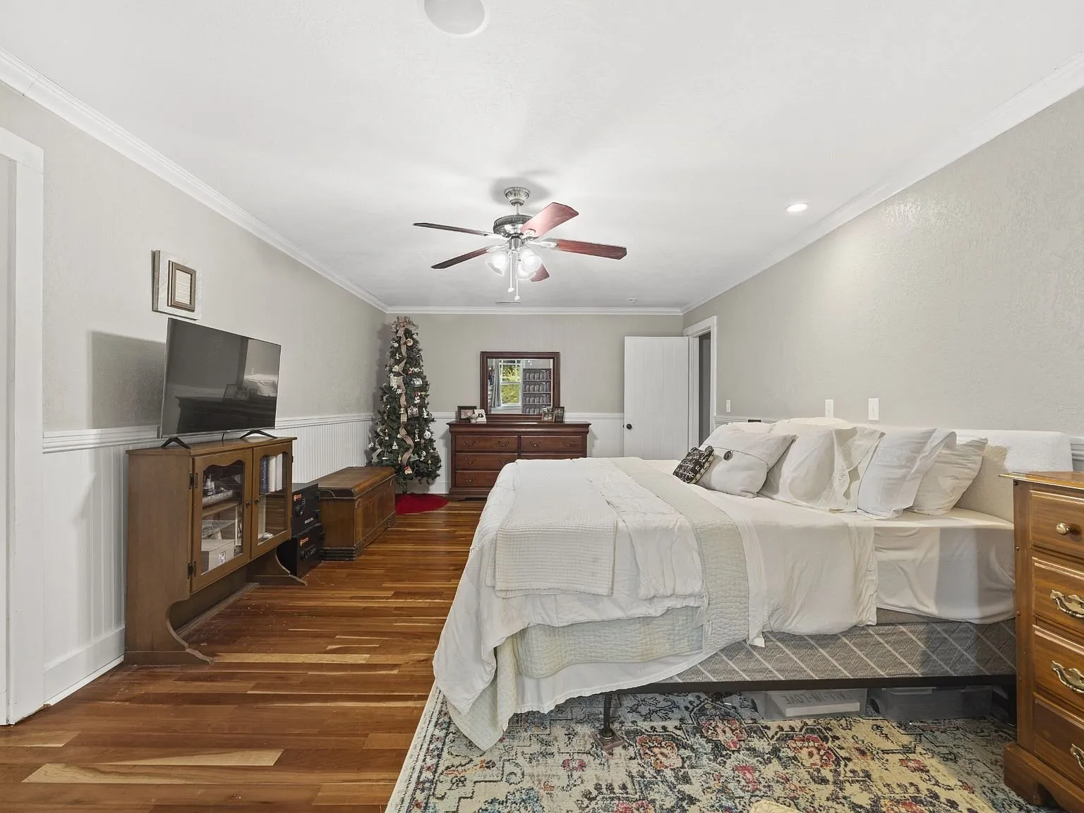 Primary bedroom with wood floors and a ceiling fan