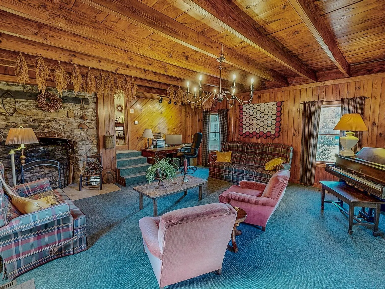 The family room with a stone fireplace, wood ceiling beams and a wraparound staircase