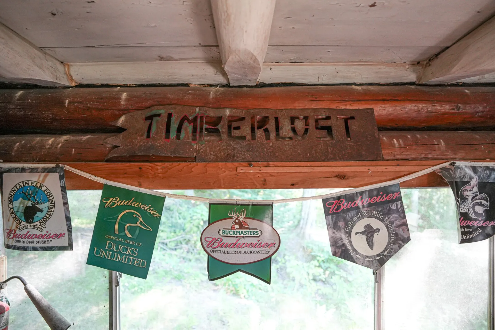 The carved Timberlost sign and camp pennants hung on the log wall