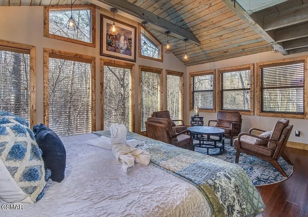 A bedroom under a cathedral ceiling with windows on two walls