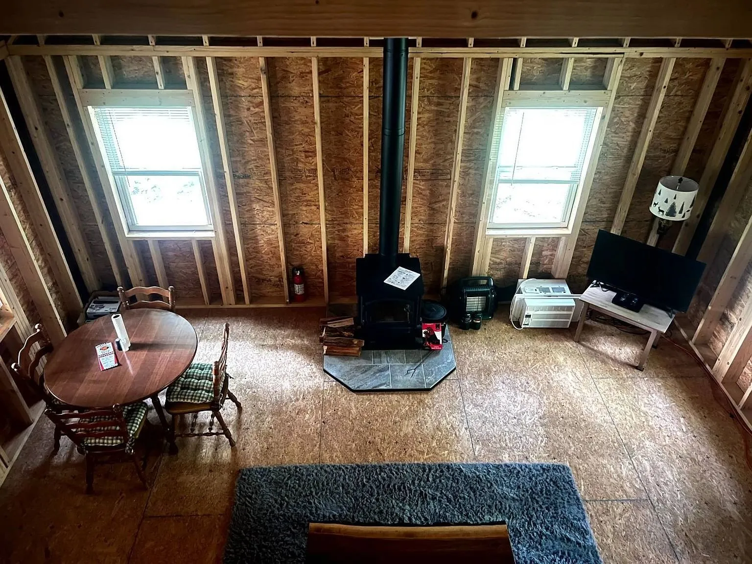 The main room with a table, the stove and windows in the bare framing