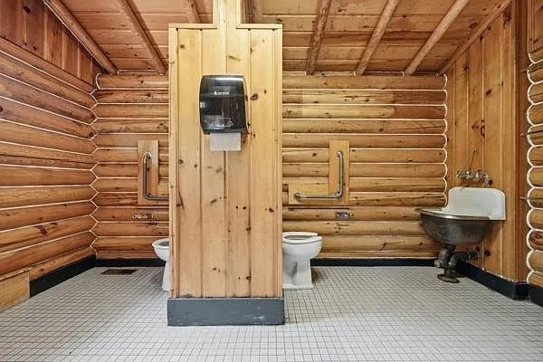 The bathroom with the toilet, the sink and the hand dryer on the log wall