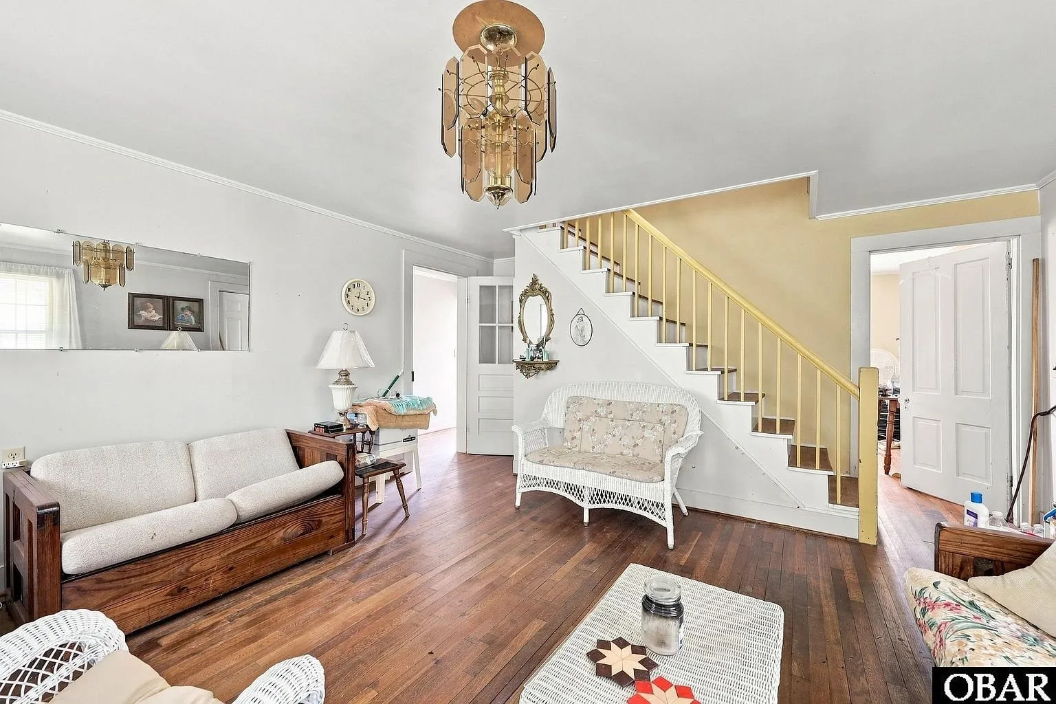 The living room with the open stair and wicker furniture