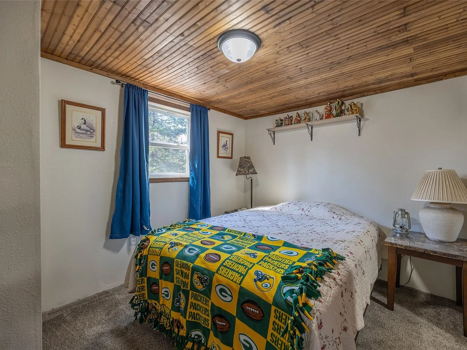 A loft-style room with a sloped wood ceiling and a small desk