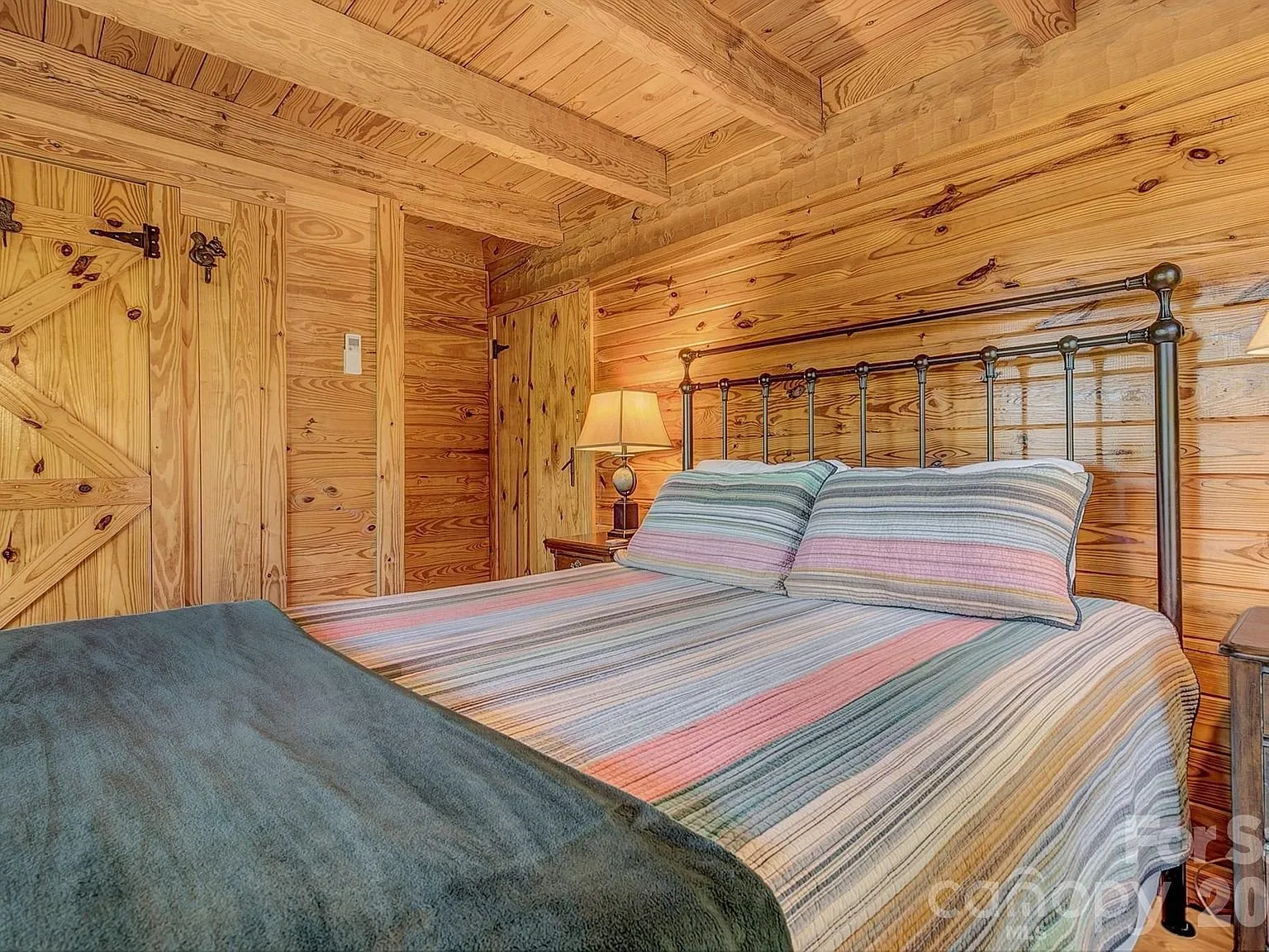 A bedroom with a striped quilt and a barn-style closet door