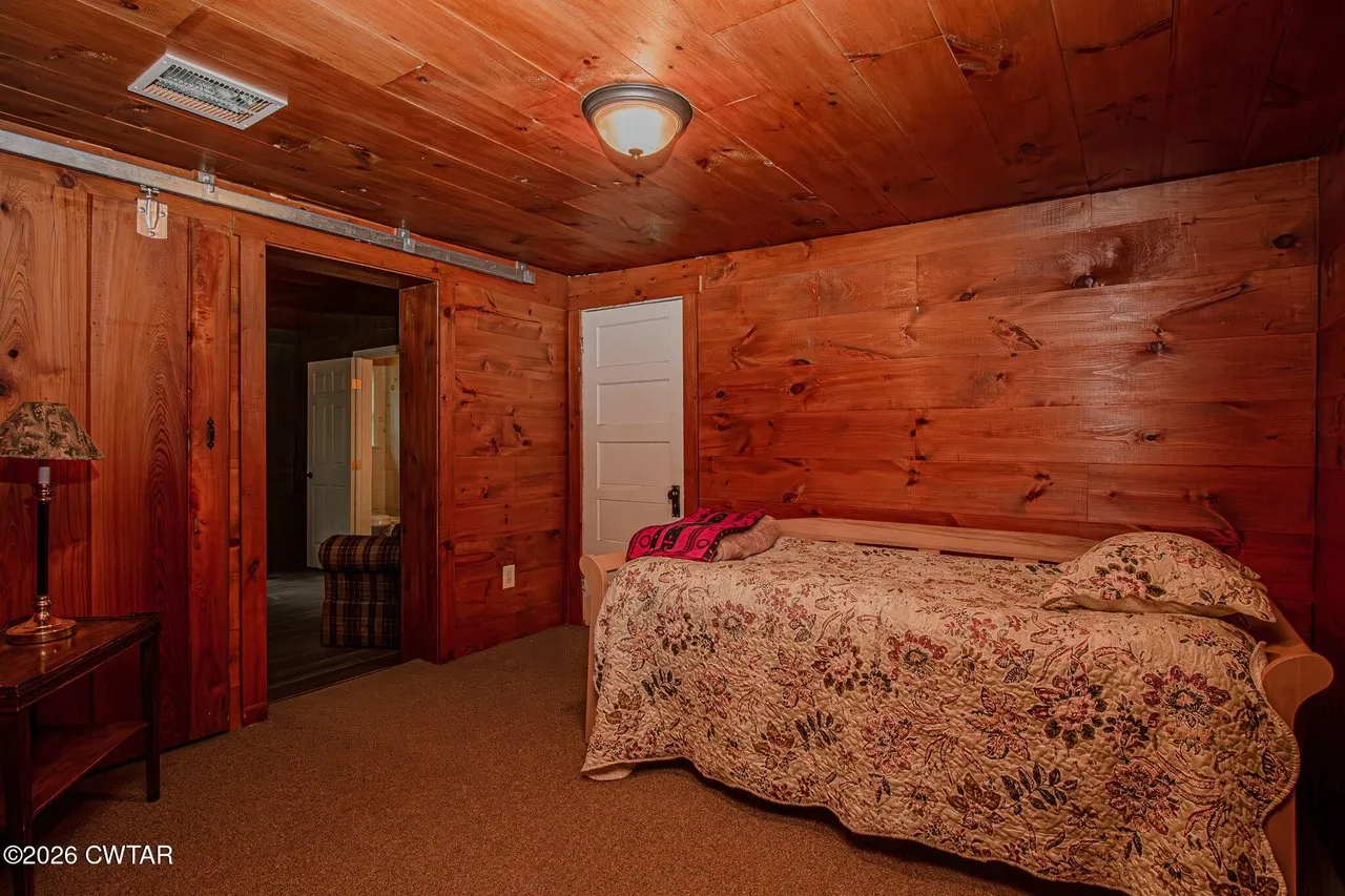 A third bedroom with wood-panelled walls and a quilted bed