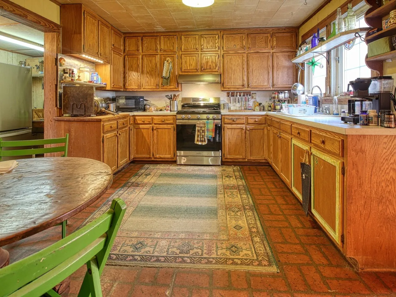 The kitchen: wood cabinets, a white range, an oval table and green chairs
