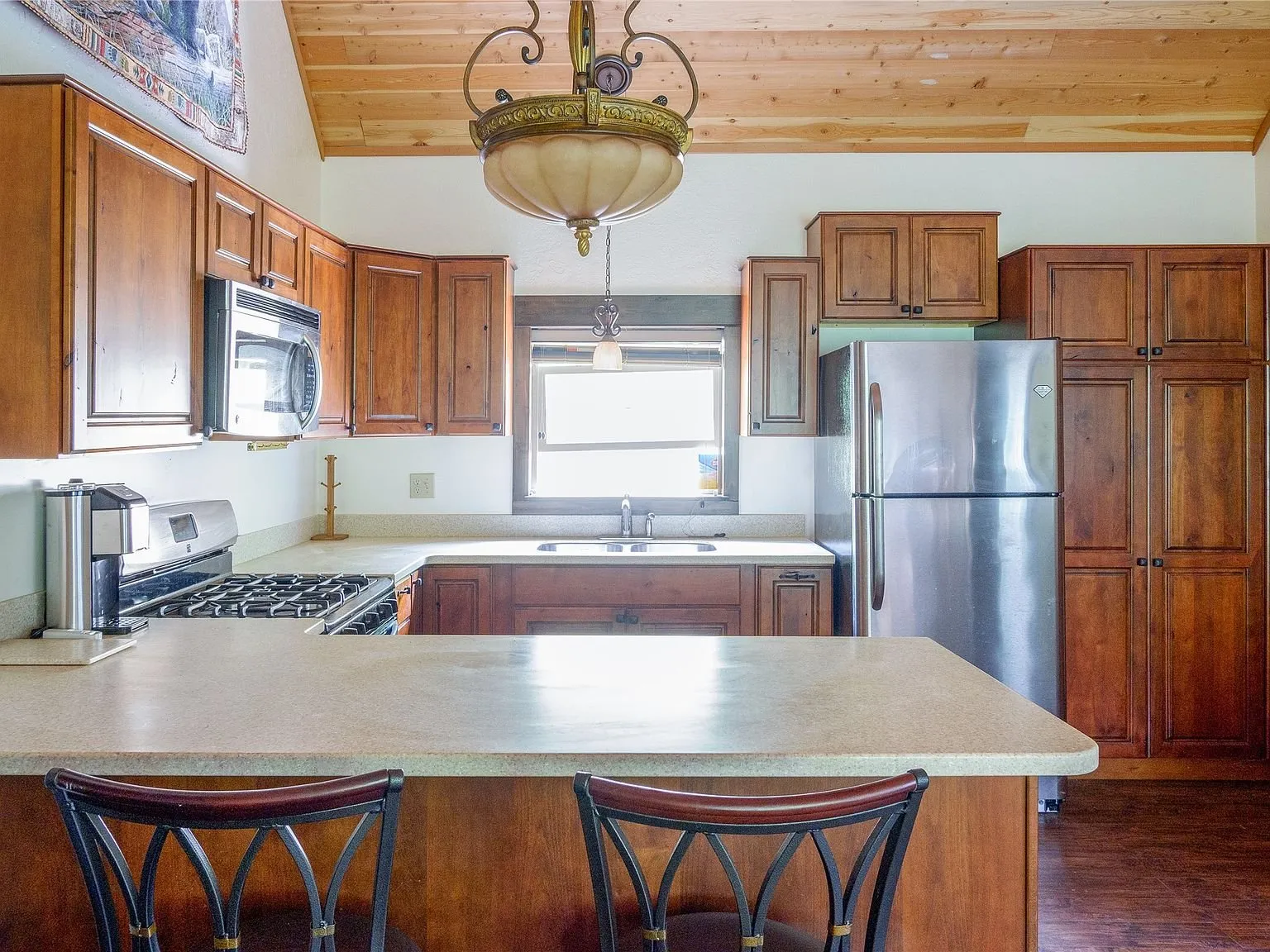 The kitchen counter and bar seating beneath a pendant light