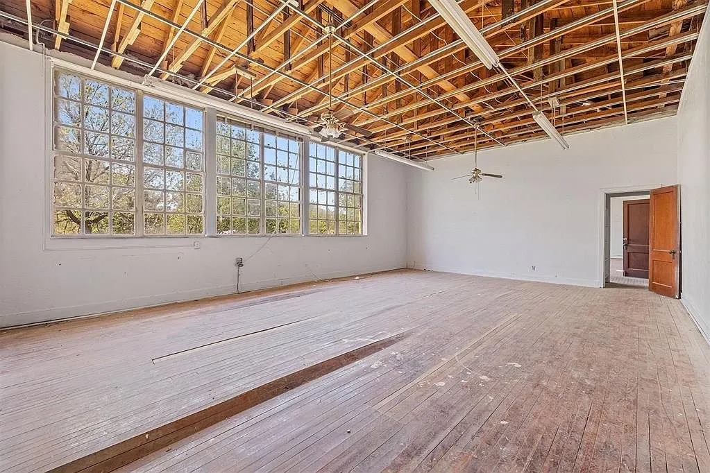 A classroom with the ceiling open, the steel windows and the doors to the hall