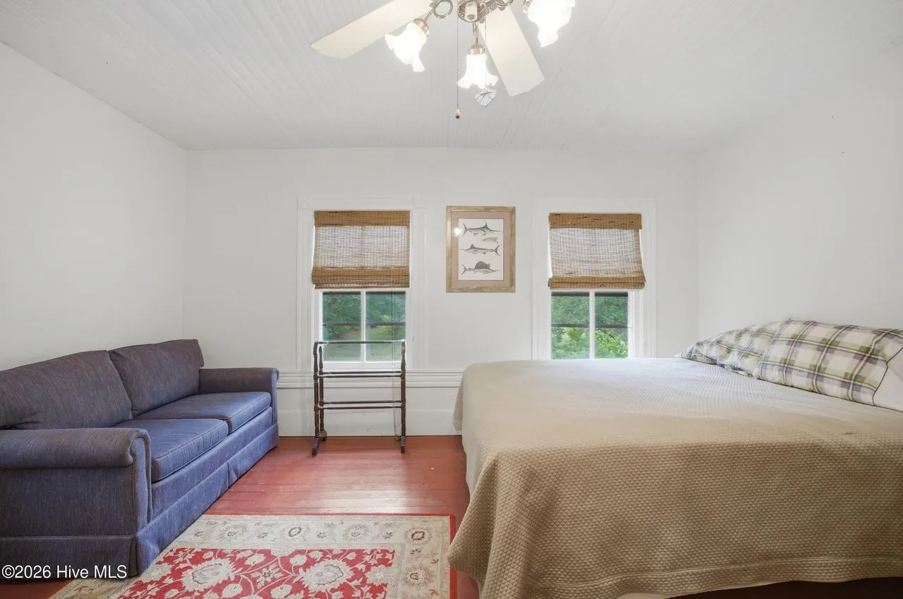 Bedroom with a painted red floor, two windows, and a daybed