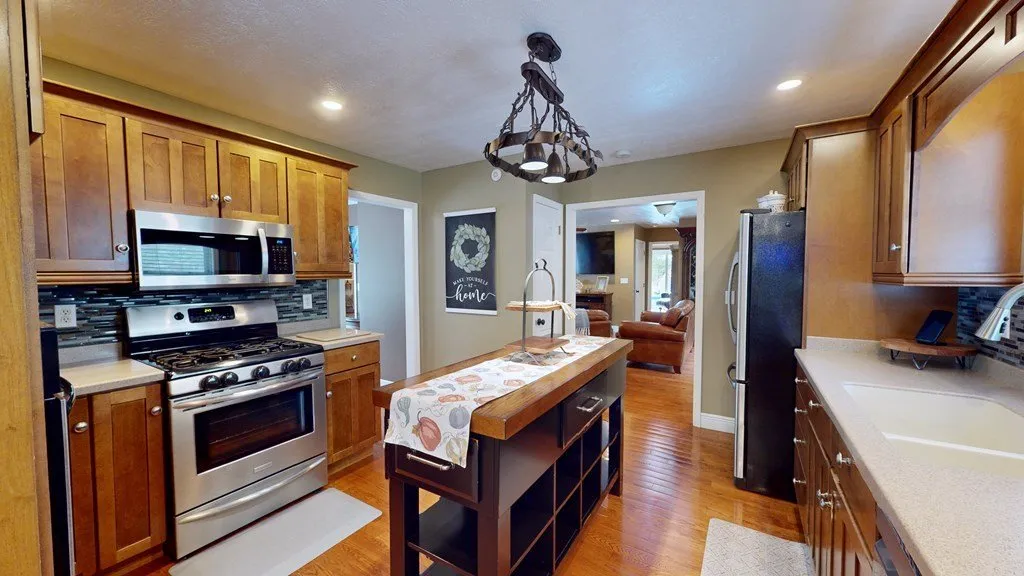 The kitchen with a stainless range, wood cabinets and a bar-height island