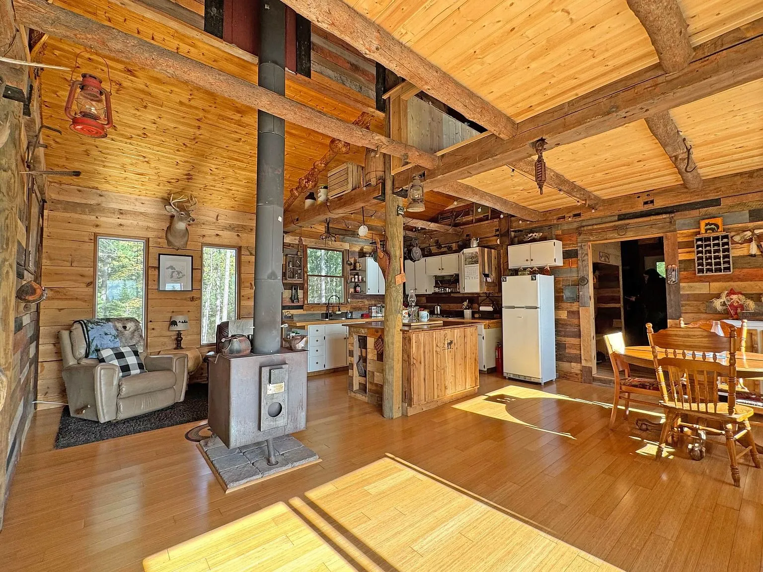 The main room with the wood stove, log posts and the kitchen beyond