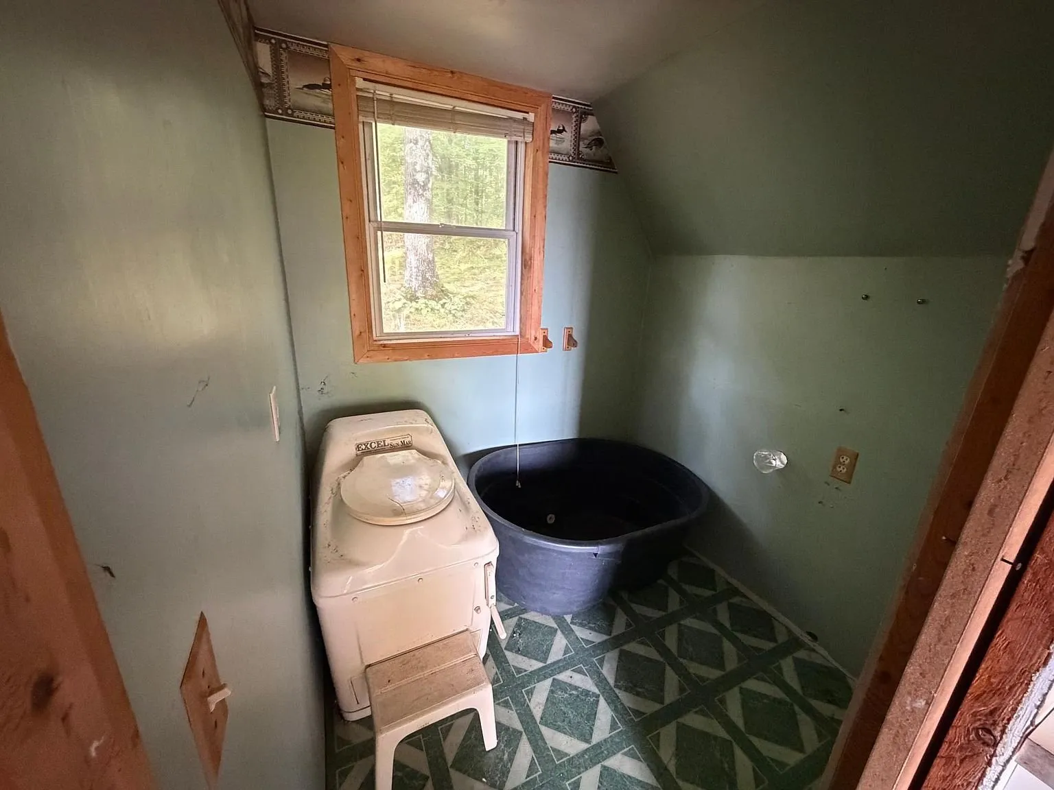 The bathroom with the composting toilet, the stock tank and the window