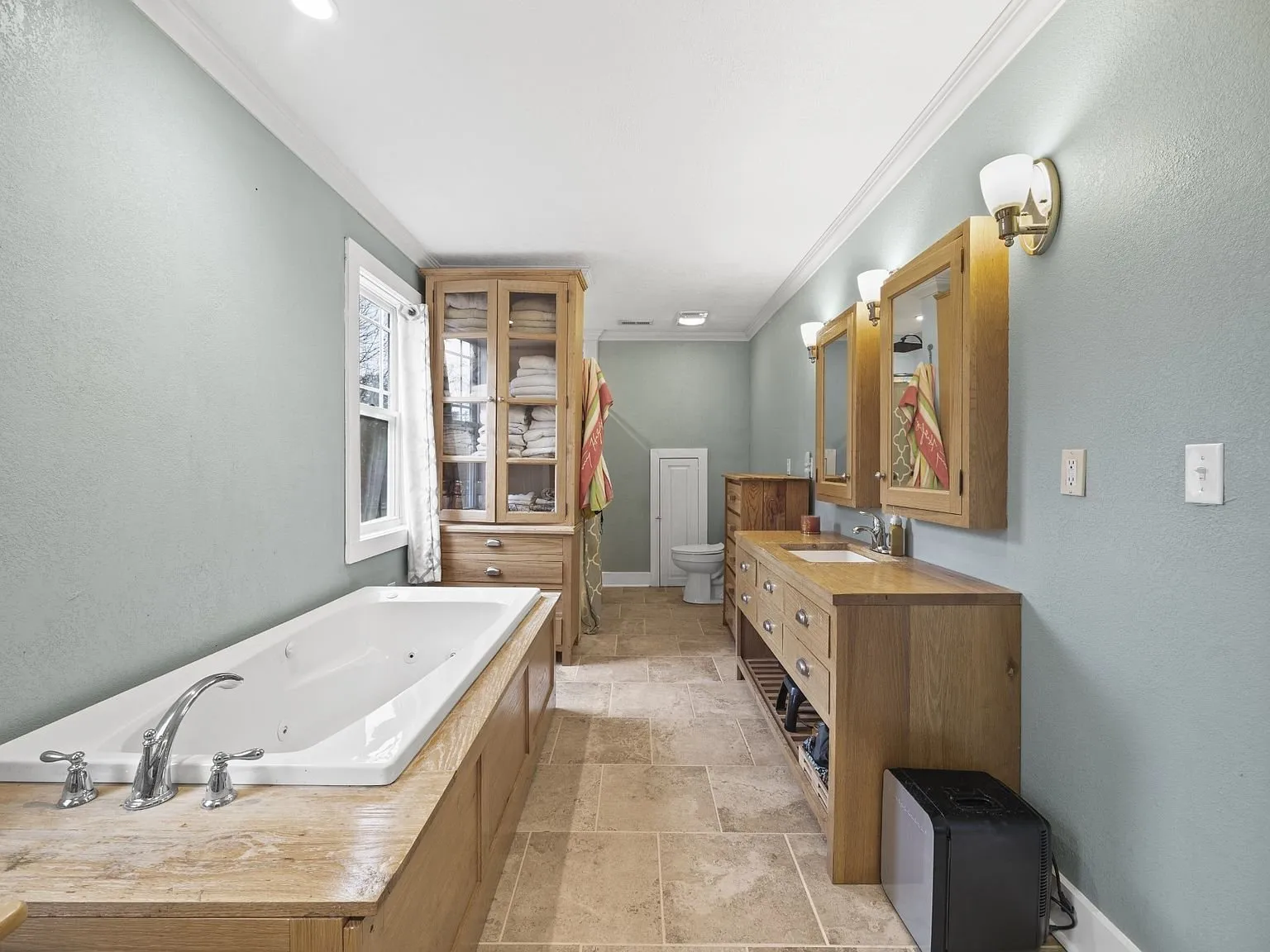 Primary bath with the jetted tub, tile floor, and wood vanity