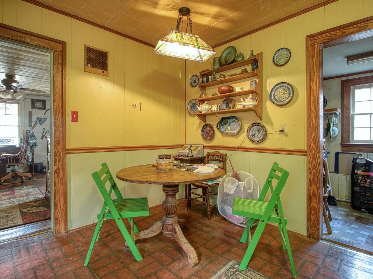 The dining corner with a round table, folding chairs and a plate rack on the wall