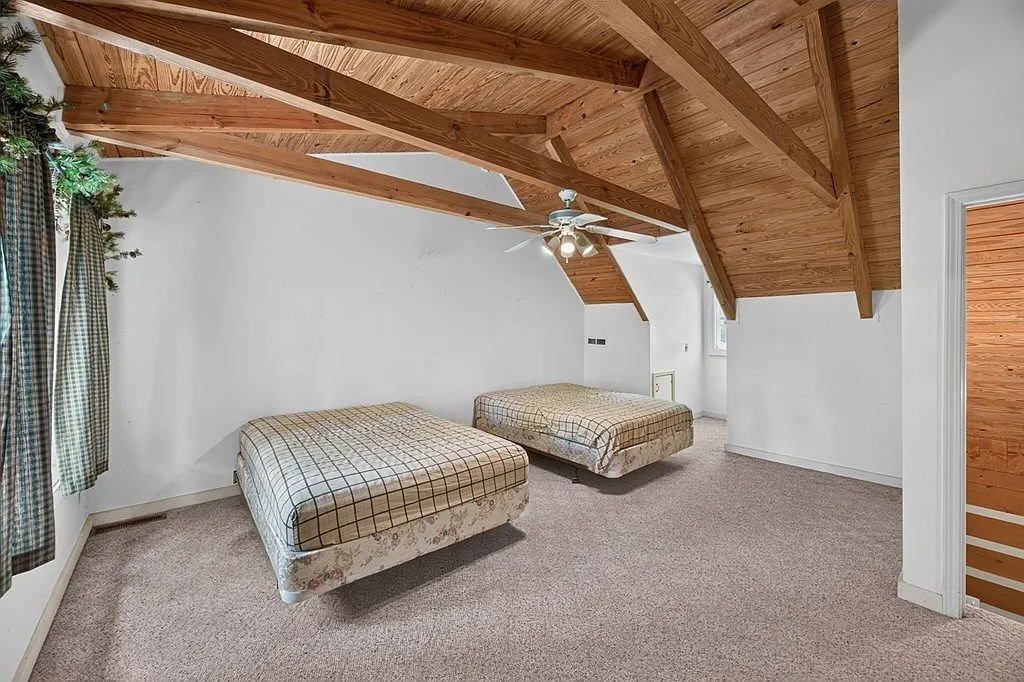 A room with two twin beds under the home's exposed roof beams