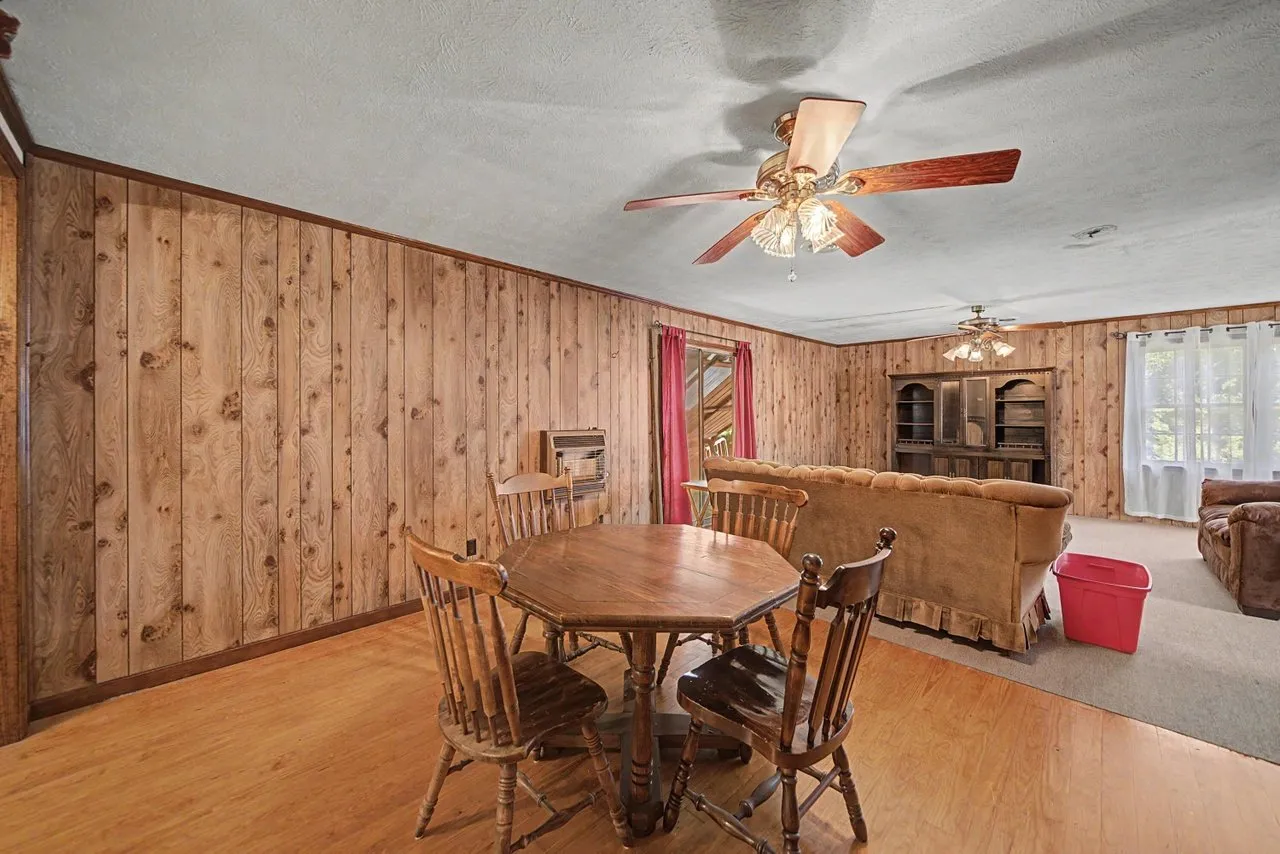 A panelled room with a round table and chairs by the window