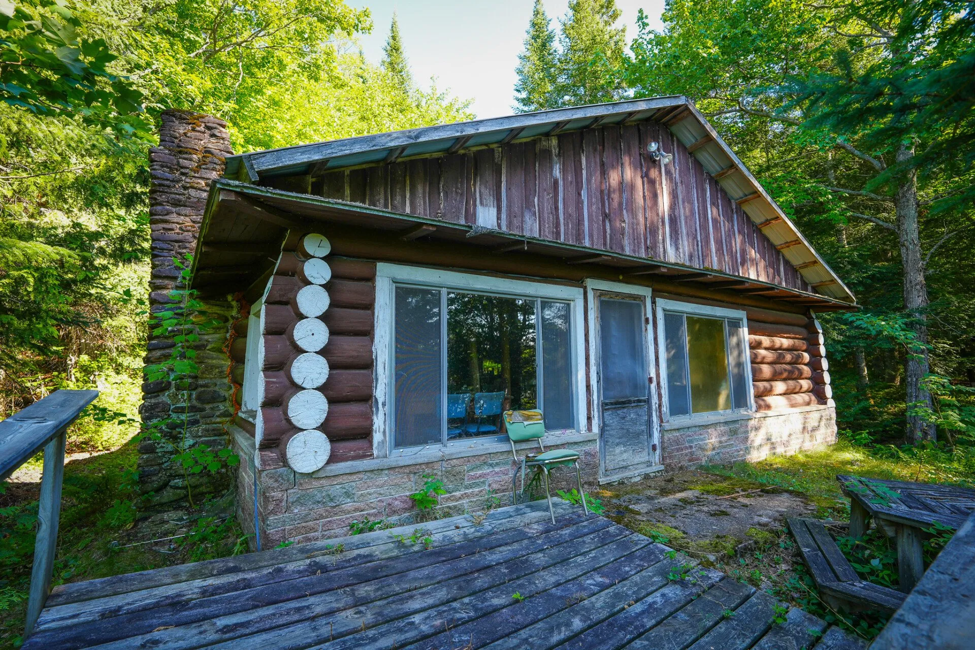 A cabin with a wall of windows and a deck set on the river bank