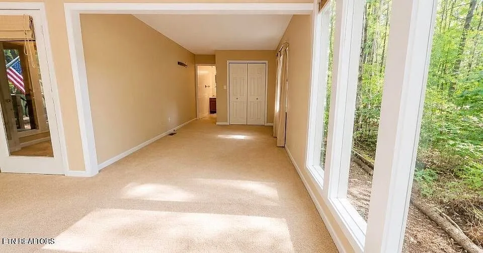 A carpeted room opening onto the glassed sunroom