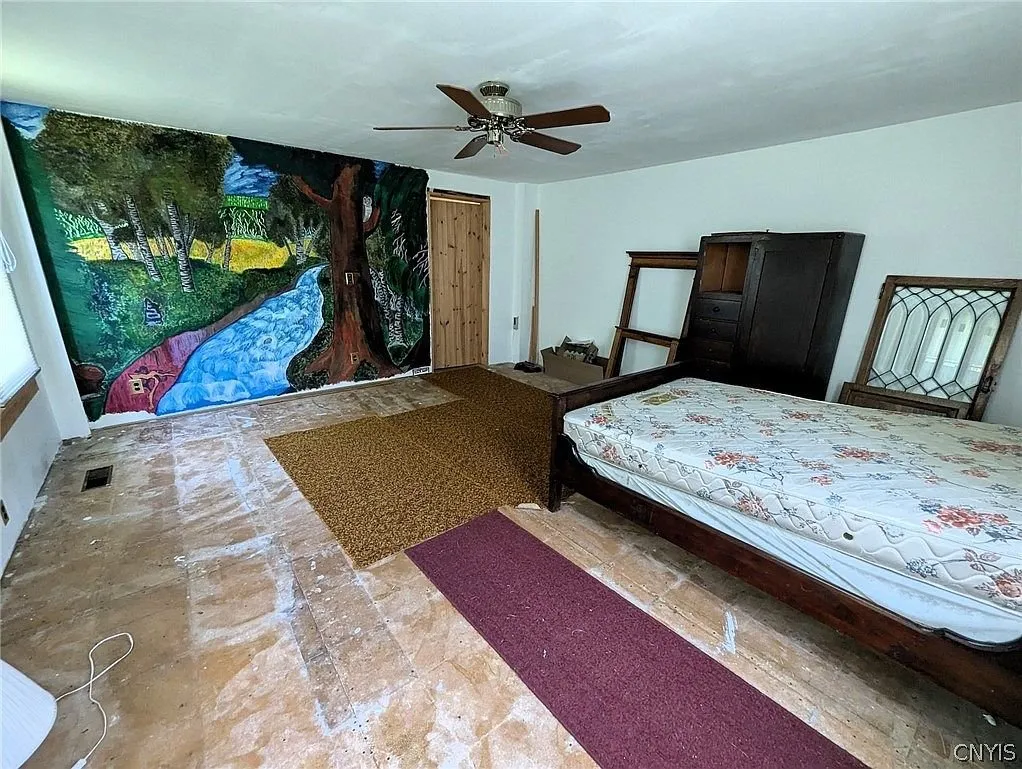 A bedroom with a painted mural on one wall and a bed on the floor