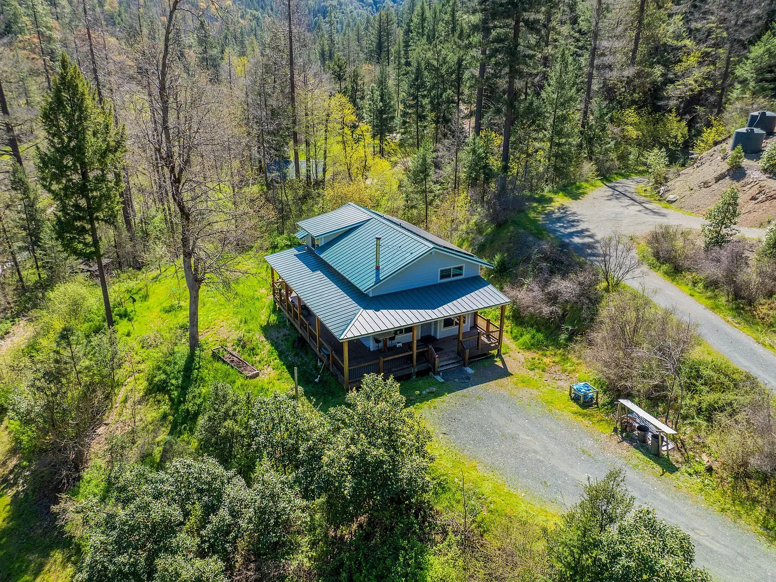 An aerial view of the house and surrounding cleared yard among the trees