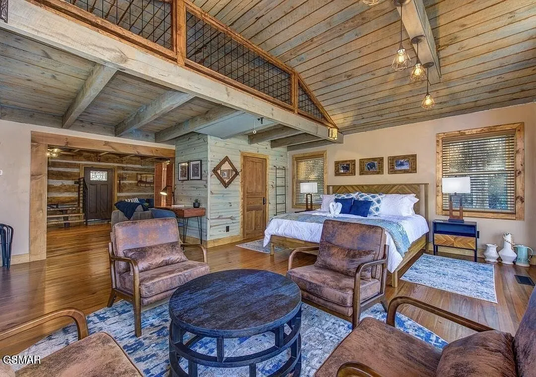 A bedroom with a bed, armchairs and the loft opening above