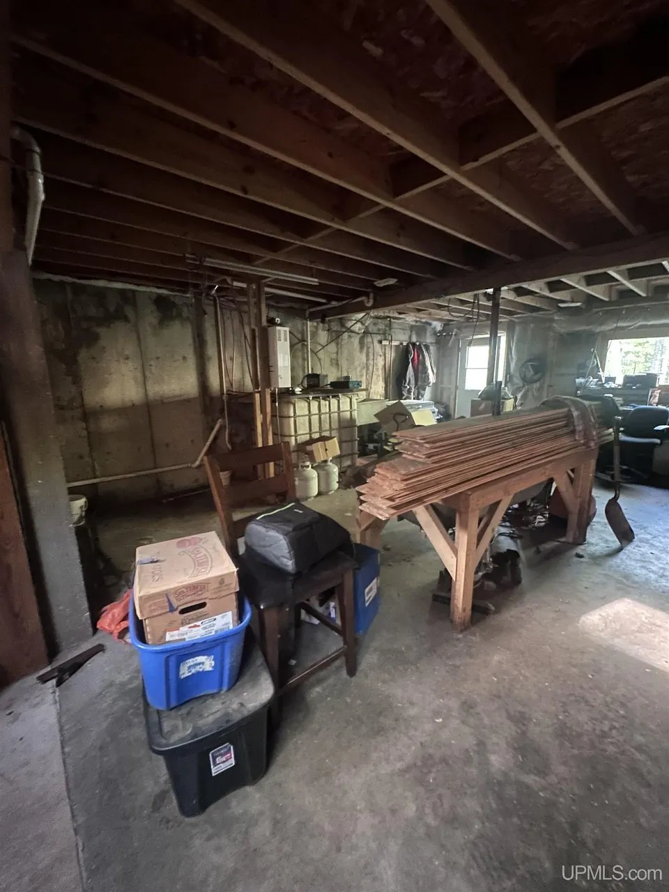 The unfinished basement with the open joists, a workbench and stacked lumber