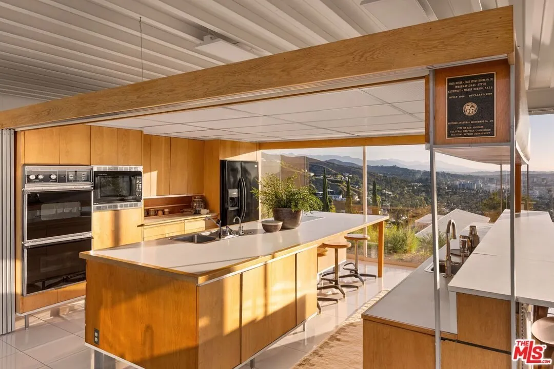 The kitchen from the dining side, wood cabinets and the wall of glass