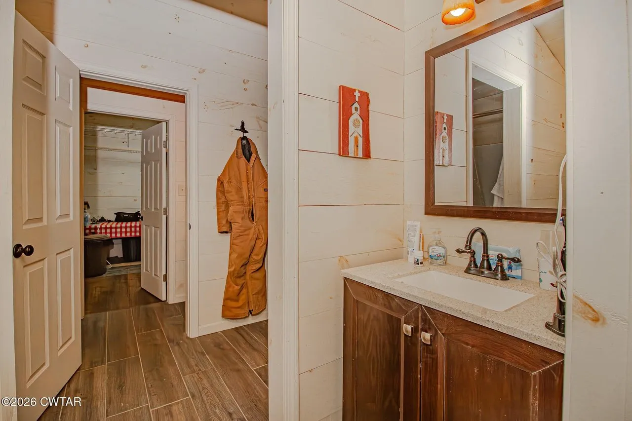 A bathroom vanity with a mirror, and the door through to the next room