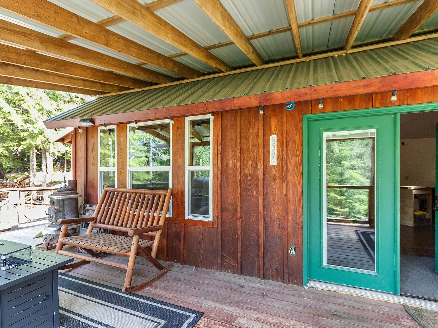 A built-in bench and green double doors on the cabin's covered deck