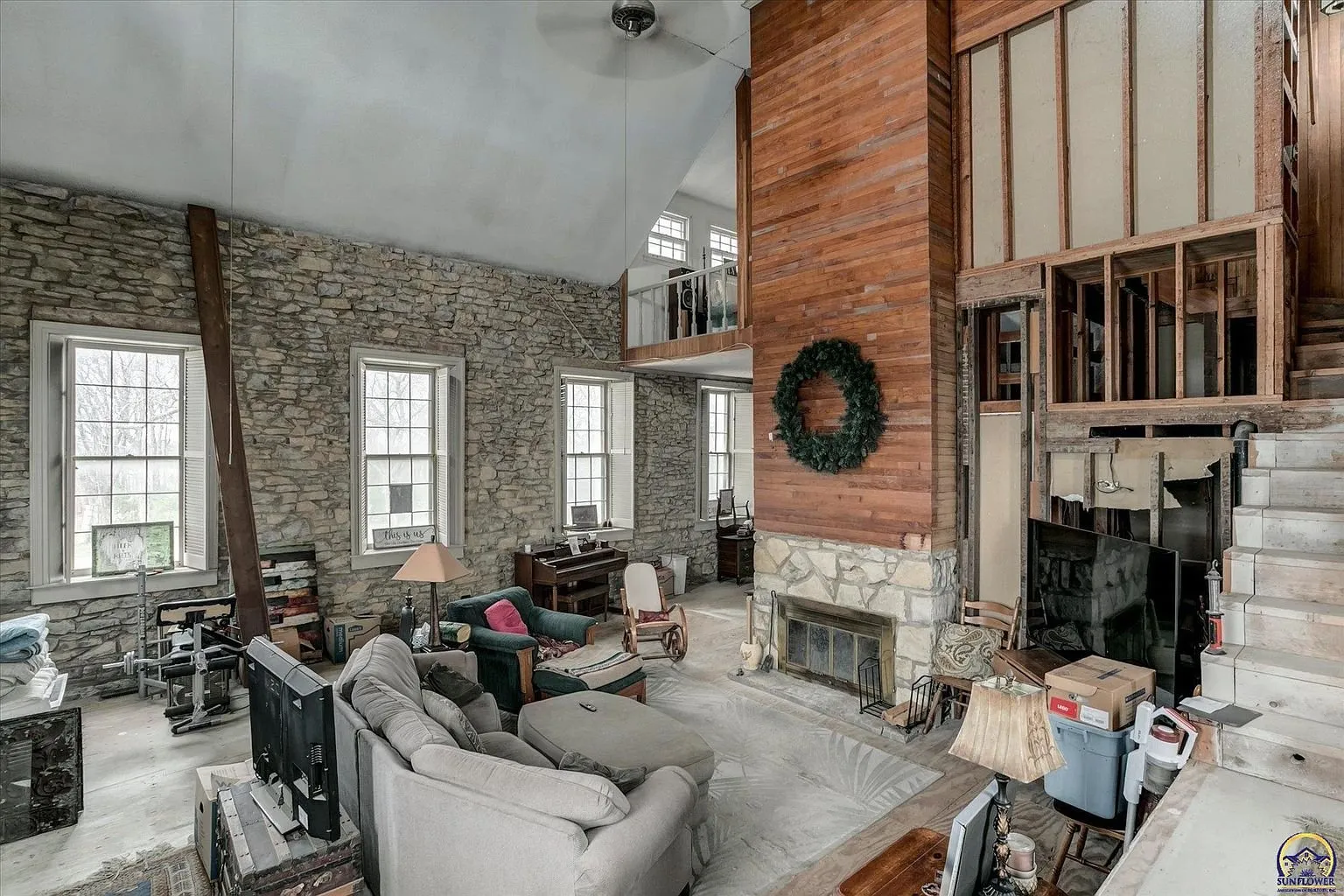 The great room with the fireplace, the stone walls and the loft rail above