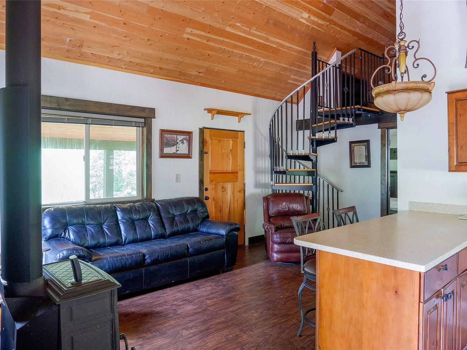 The living area's wood stove and leather seating, open to the kitchen