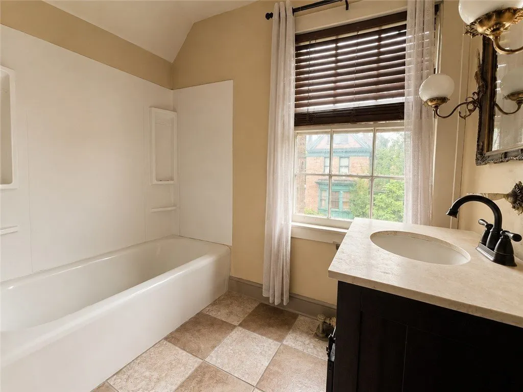 A bathroom with a tub, a vanity and a window