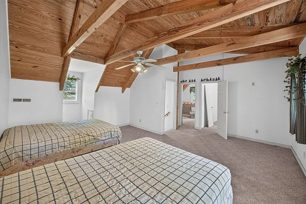 A bedroom with a full bed under the exposed wood ceiling beams