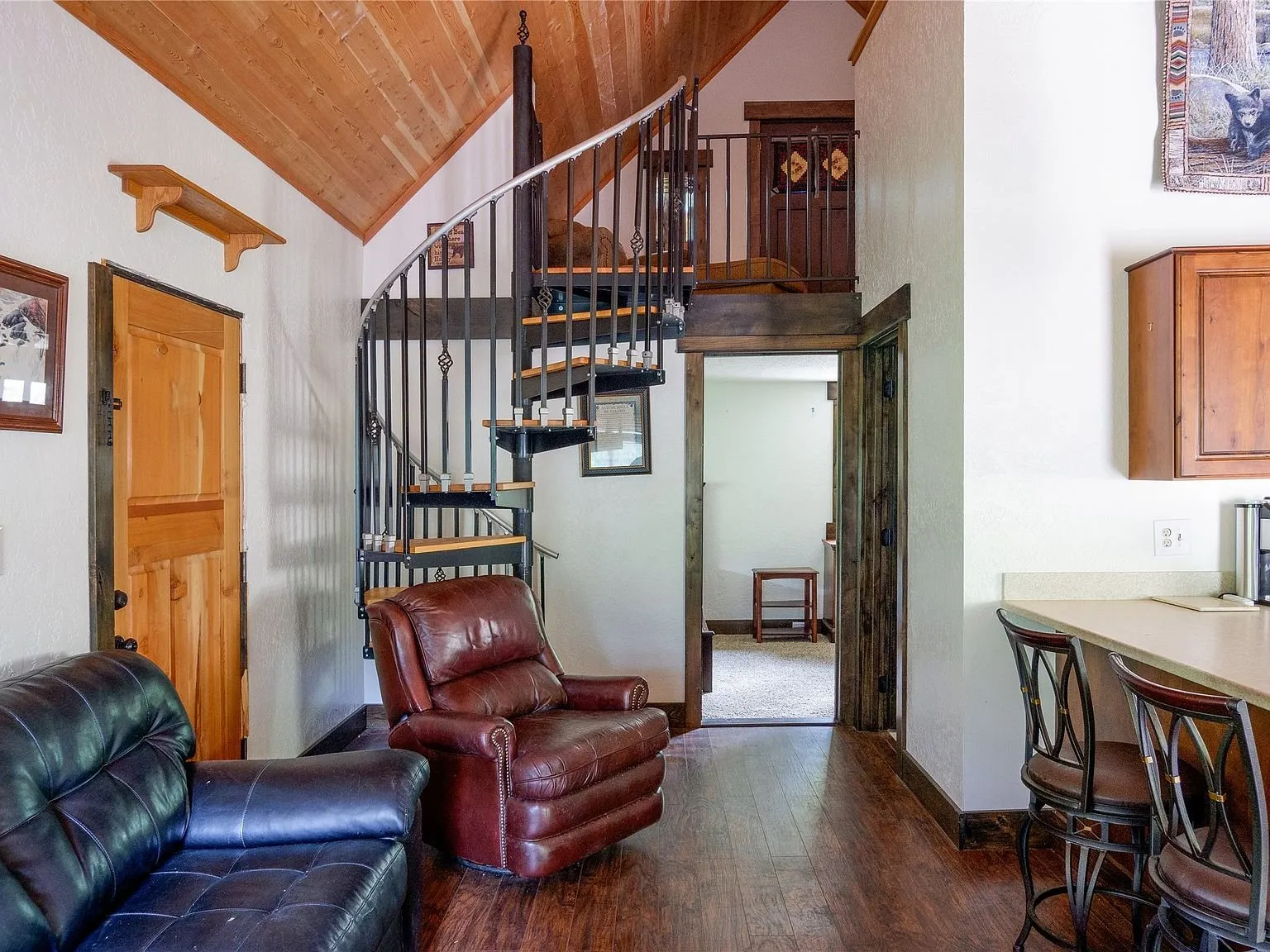 The living room with a spiral staircase to the loft and a leather recliner