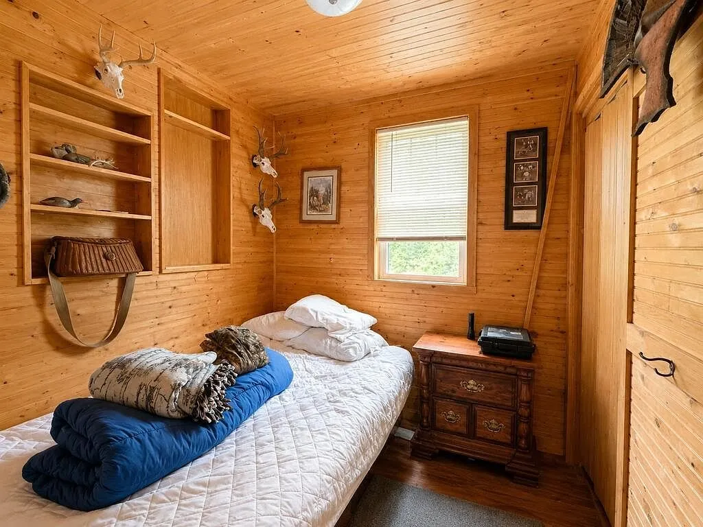 A bedroom with a bed and shelving on the pine wall