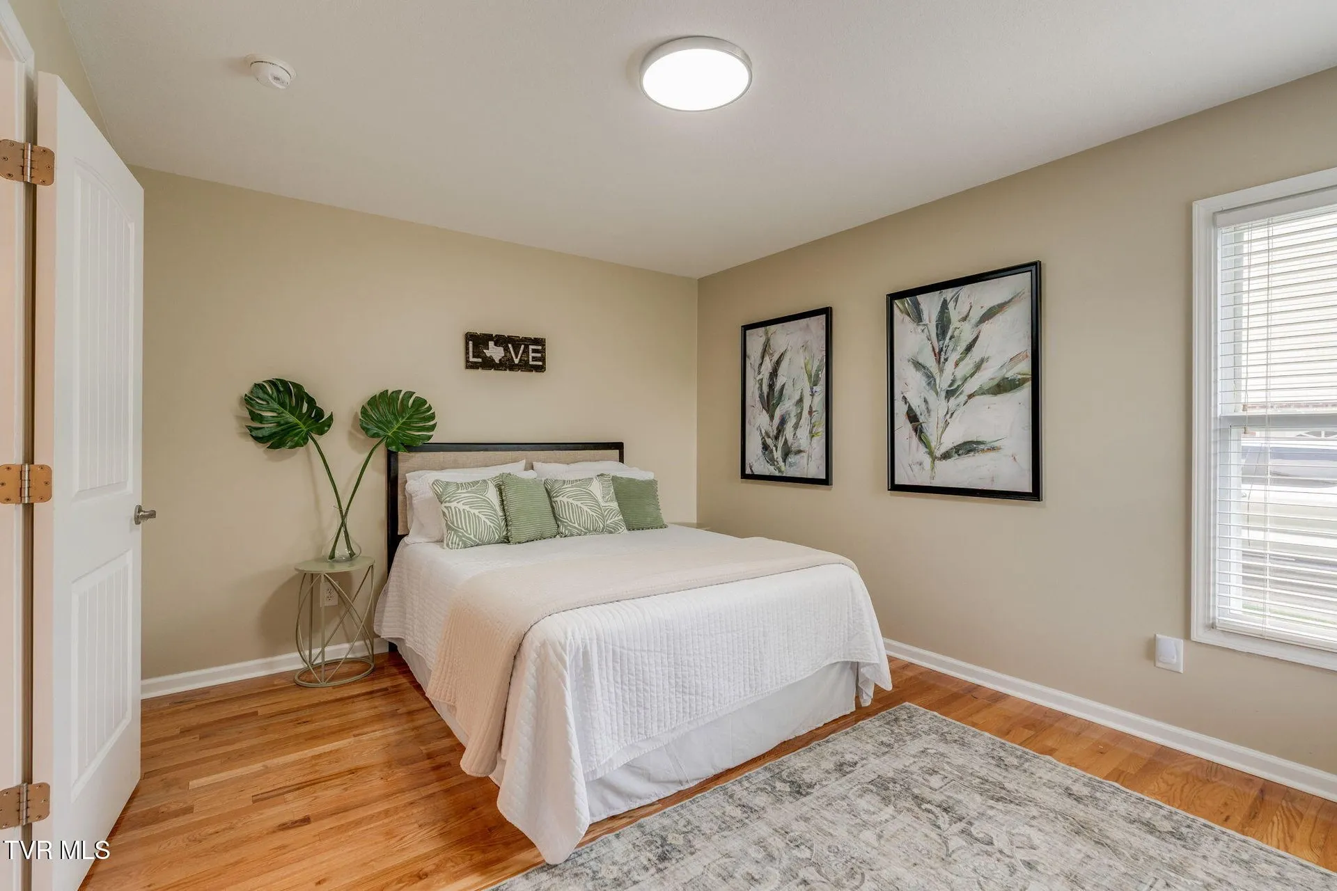 The main-floor bedroom with a bed, framed prints and a window