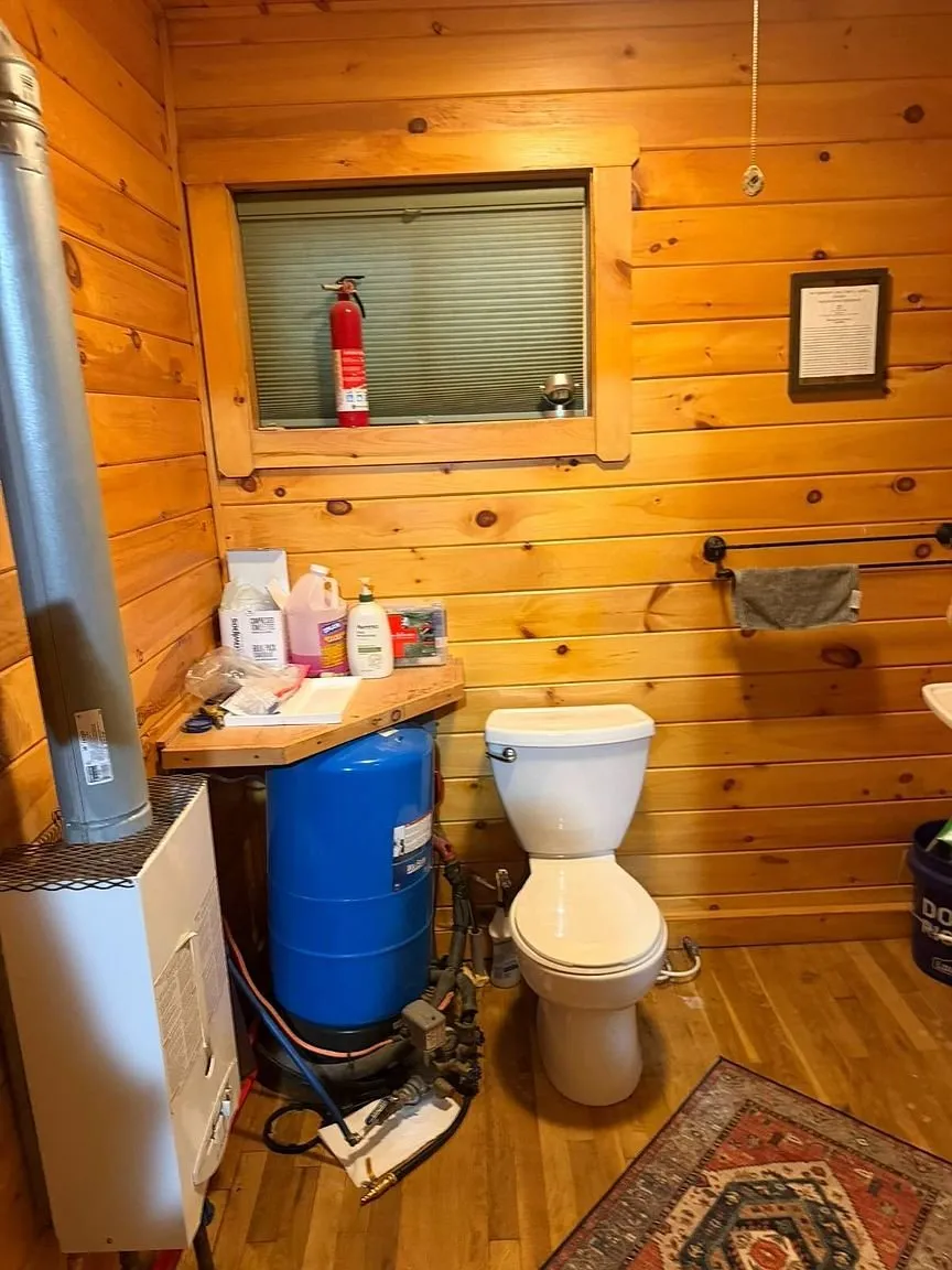 The bathroom with the toilet, a blue drum and the window