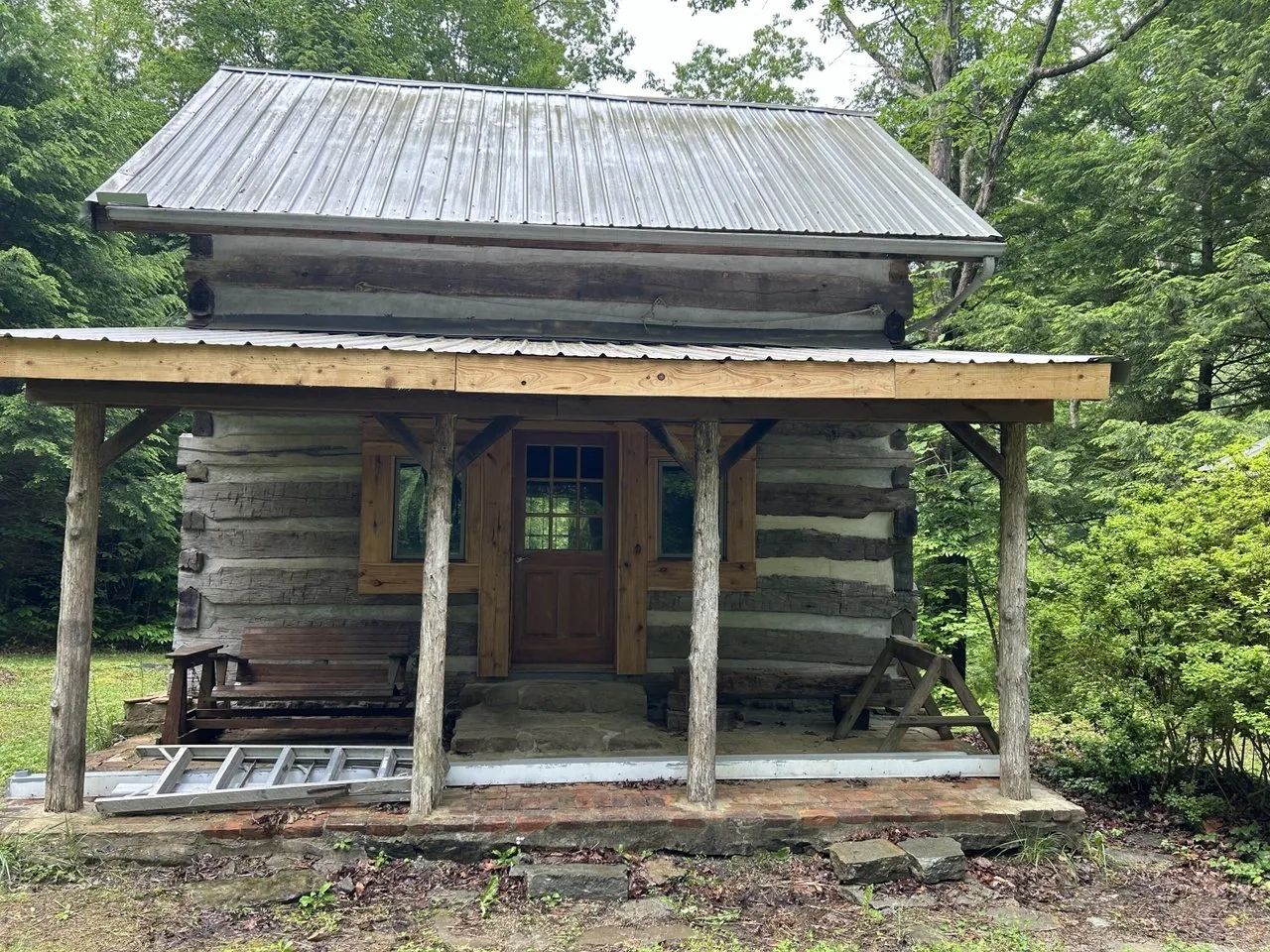 The log cabin from the front, showing the porch posts and the loft window